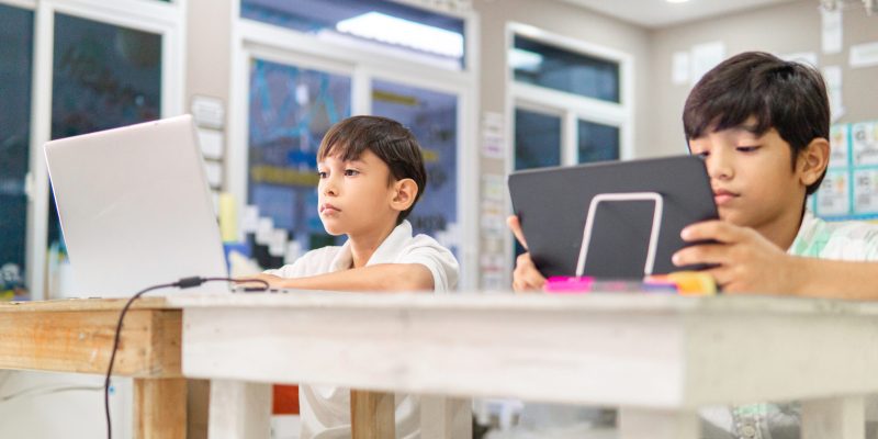 Portrait of latin american children students using a laptops and Digital Tablet in a classroom.